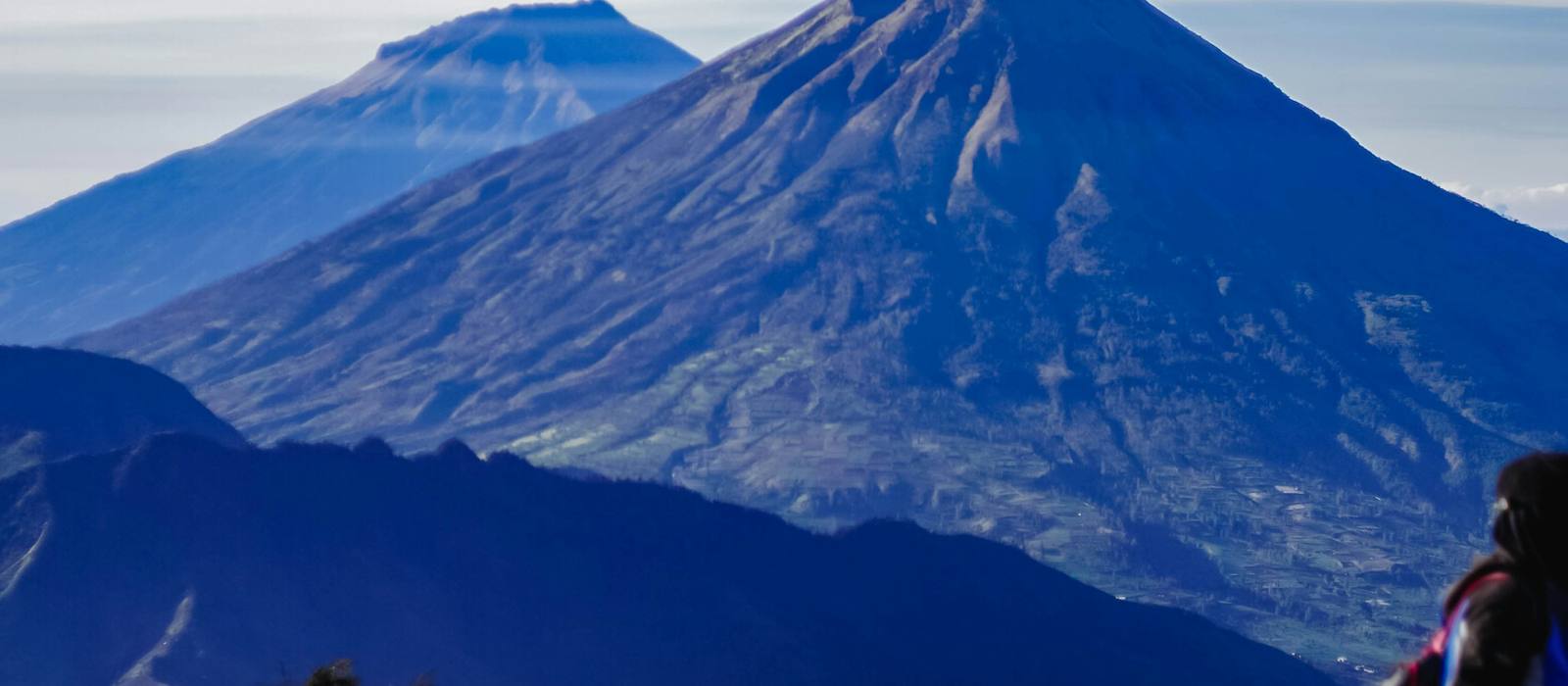 Volcanic peaks rising above the clouds, seen from a high backpacking camp