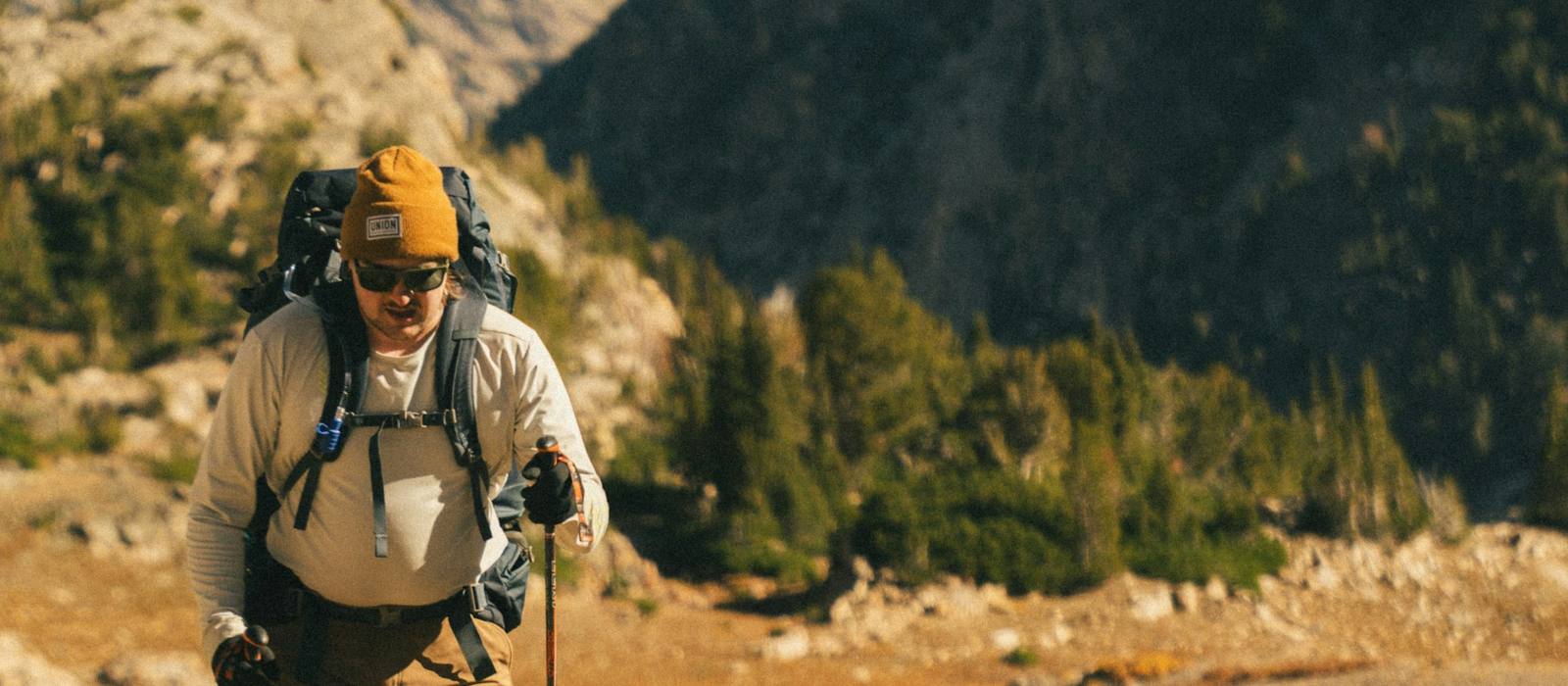 Backpacker with a loaded pack on a rocky trail in autumn mountains
