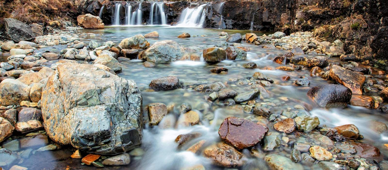 Clear mountain stream tumbling over rocks below rugged peaks